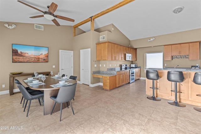 kitchen featuring range with two ovens, high vaulted ceiling, a breakfast bar area, baseboards, and ceiling fan