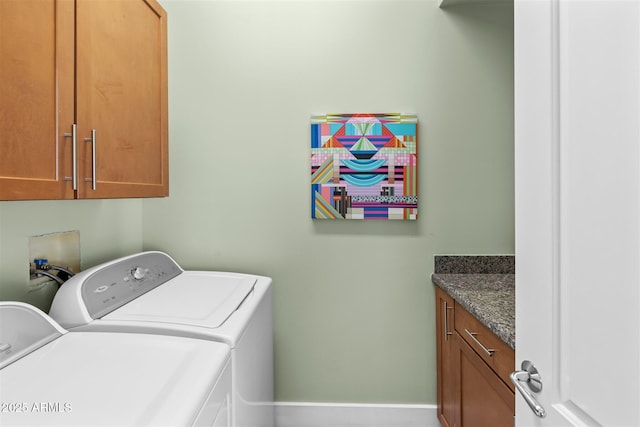 clothes washing area featuring separate washer and dryer, cabinet space, and baseboards