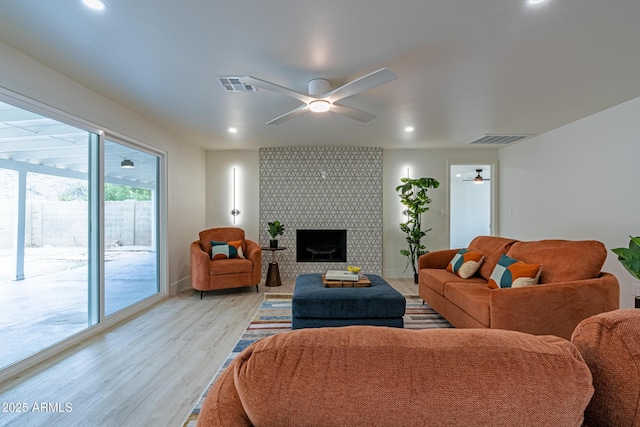 living room featuring ceiling fan, a fireplace, and light hardwood / wood-style floors