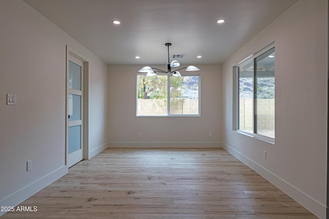 unfurnished dining area with an inviting chandelier and light hardwood / wood-style flooring