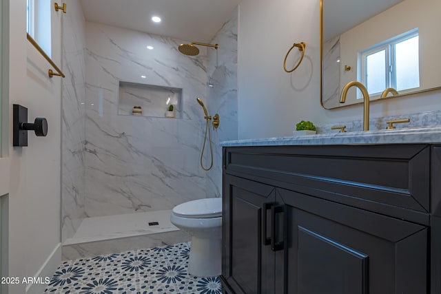 bathroom featuring vanity, a tile shower, and toilet