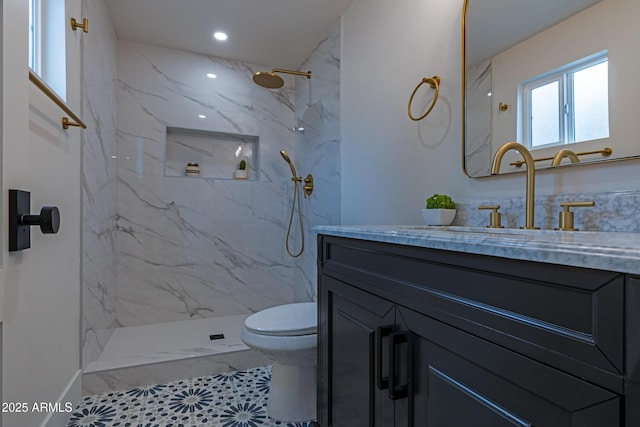 bathroom with tiled shower, vanity, and toilet