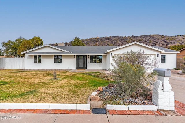 ranch-style house featuring a garage, a mountain view, and a front lawn