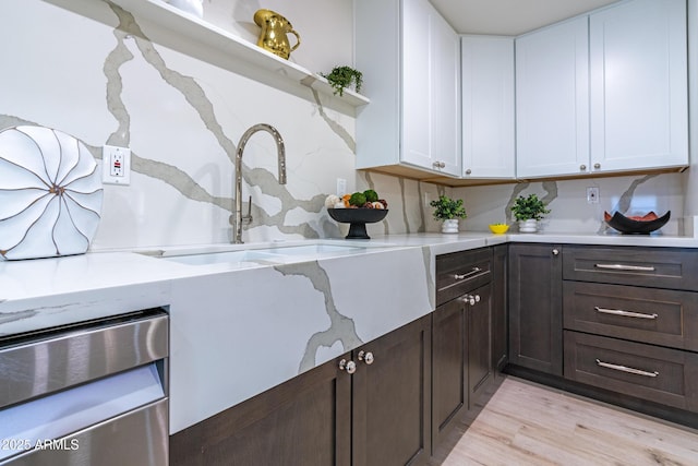 kitchen featuring dishwashing machine, sink, white cabinets, and light wood-type flooring