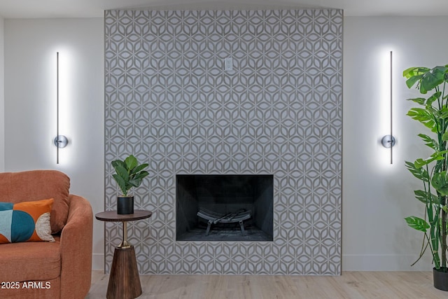 sitting room with a tiled fireplace and light wood-type flooring