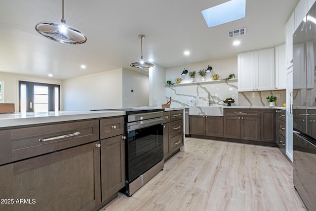 kitchen with white cabinetry, a skylight, dark brown cabinetry, light hardwood / wood-style floors, and stainless steel range with electric cooktop