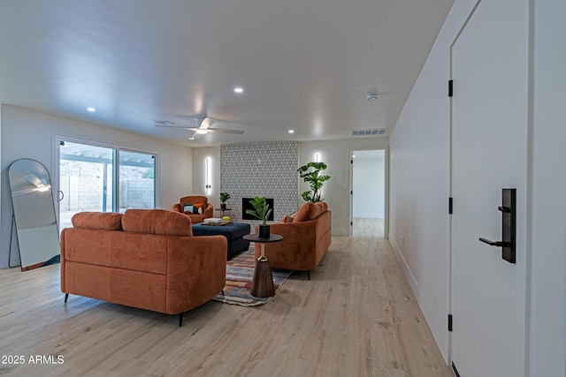 living room featuring a fireplace, light hardwood / wood-style floors, and ceiling fan