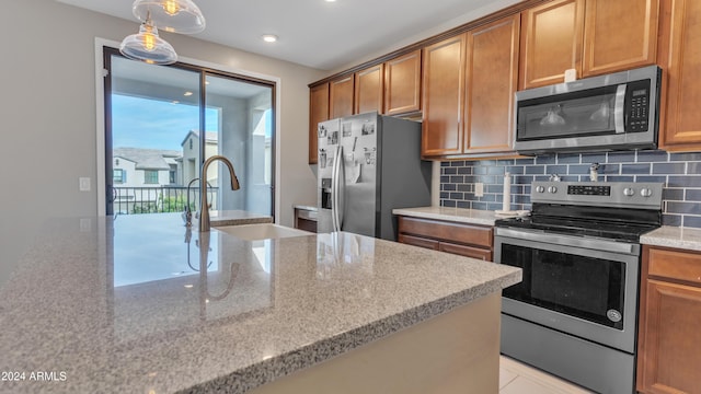 kitchen featuring backsplash, light stone countertops, sink, and stainless steel appliances