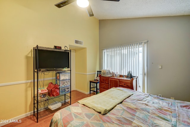 bedroom featuring high vaulted ceiling, ceiling fan, wood-type flooring, and a textured ceiling