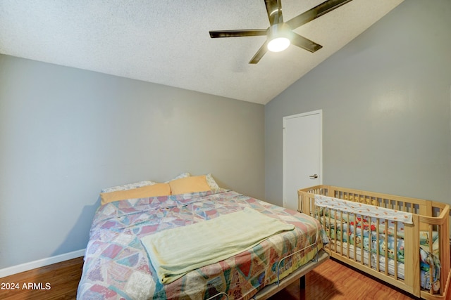 bedroom featuring hardwood / wood-style floors, ceiling fan, lofted ceiling, and a textured ceiling