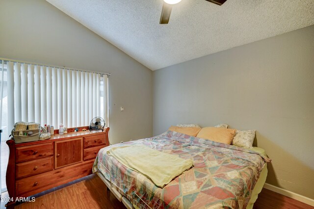 bedroom with a textured ceiling, ceiling fan, wood-type flooring, and lofted ceiling