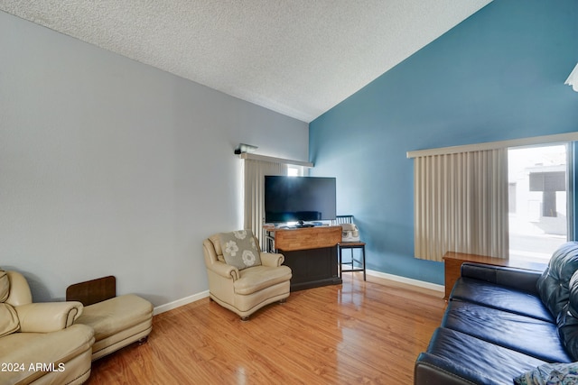 living room with hardwood / wood-style floors, high vaulted ceiling, and a textured ceiling