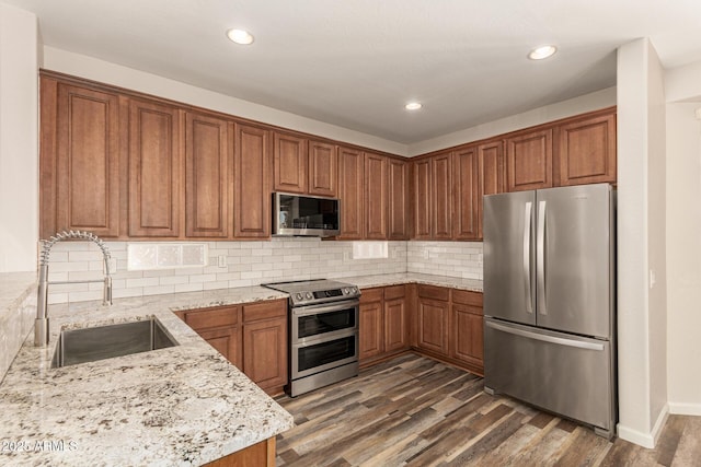 17493 N Costa Brava Ave, Maricopa, AZ 85139 - kitchen featuring stainless steel appliances, brown cabinetry, light stone countertops, dark wood finished floors, and recessed lighting
