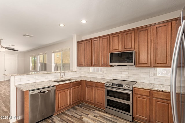 17493 N Costa Brava Ave, Maricopa, AZ 85139 - kitchen with stainless steel appliances, brown cabinets, wood finished floors, tasteful backsplash, and recessed lighting