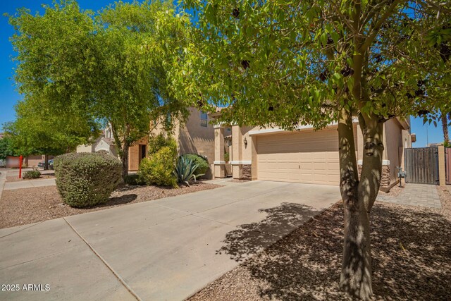 17493 N Costa Brava Ave, Maricopa, AZ 85139 - view of property hidden behind natural elements featuring driveway, stucco siding, stone siding, and a gate