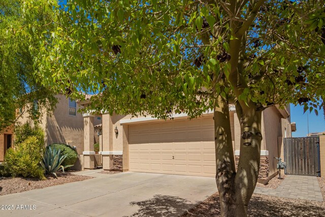 17493 N Costa Brava Ave, Maricopa, AZ 85139 - view of property hidden behind natural elements featuring stucco siding, concrete driveway, stone siding, and an attached garage