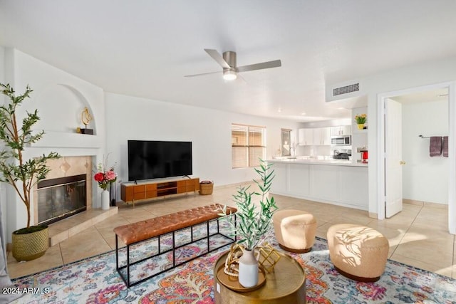 living room with ceiling fan, light tile patterned floors, and a tile fireplace