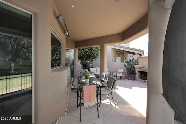 view of patio featuring outdoor dining area, fence, and an outdoor fireplace