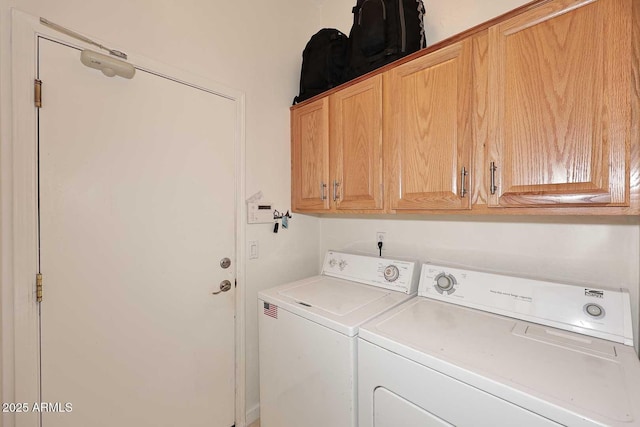 clothes washing area featuring washing machine and dryer and cabinet space