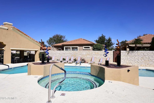 community pool featuring a community hot tub, a fenced backyard, and a patio