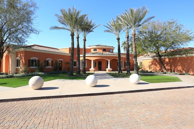 view of front of house with stucco siding, a front lawn, and a tiled roof