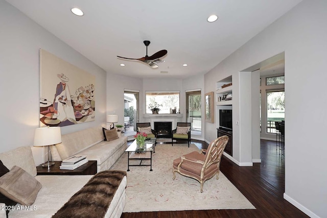 living room with recessed lighting, a fireplace, wood finished floors, and baseboards