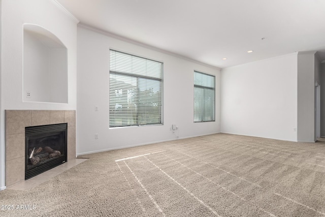 unfurnished living room with a fireplace, light colored carpet, plenty of natural light, and crown molding