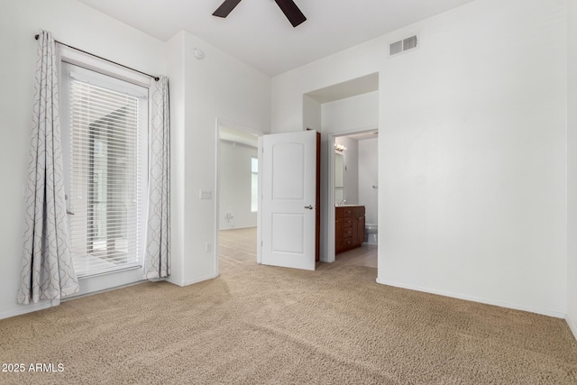 unfurnished bedroom featuring light colored carpet, ensuite bath, and ceiling fan