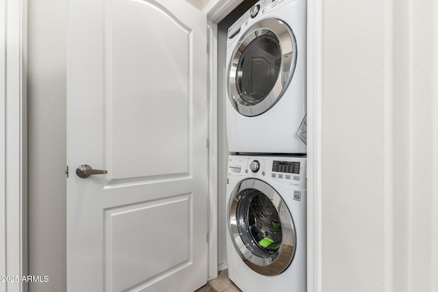 laundry room featuring stacked washer / drying machine and light tile patterned flooring