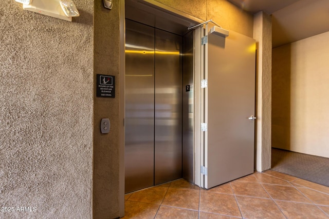 hall featuring elevator and tile patterned flooring