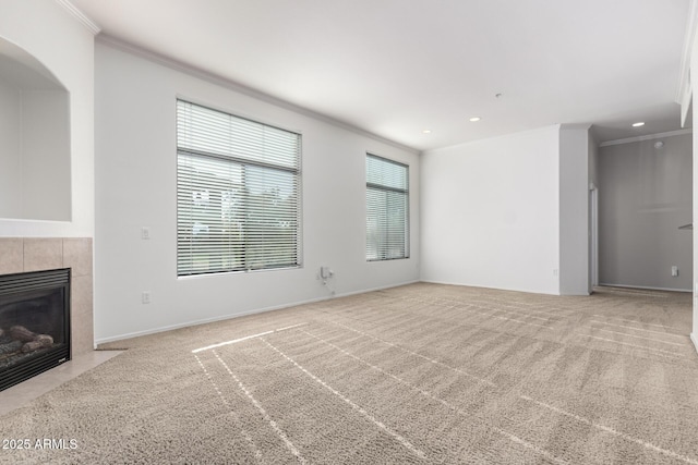 unfurnished living room with a tiled fireplace, light carpet, and a healthy amount of sunlight