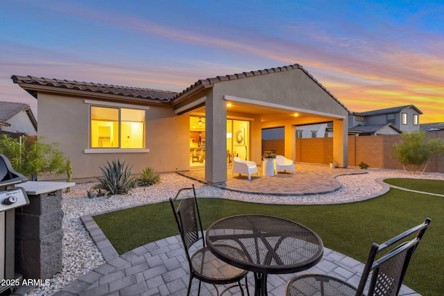 19908 W Montecito Ave, Litchfield Park, AZ 85340 - back of property at dusk featuring a patio, stucco siding, outdoor dining space, and a tiled roof