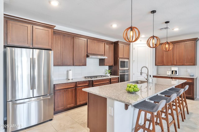 19908 W Montecito Ave, Litchfield Park, AZ 85340 - kitchen featuring appliances with stainless steel finishes, under cabinet range hood, light stone counters, a breakfast bar, and decorative backsplash