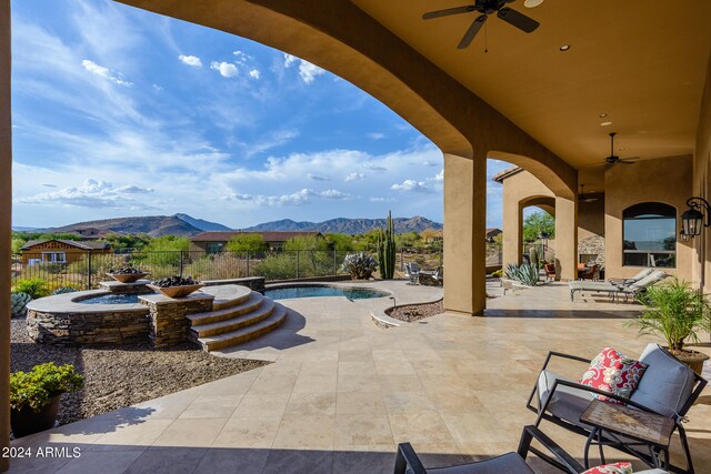 view of terrace featuring ceiling fan, a mountain view, and a fenced in pool