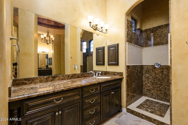 bathroom with tiled shower, tile floors, large vanity, and a notable chandelier