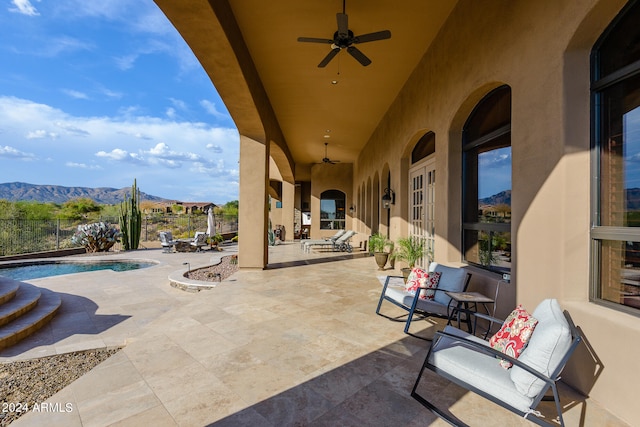 view of patio / terrace featuring an outdoor living space, ceiling fan, a mountain view, and a fenced in pool