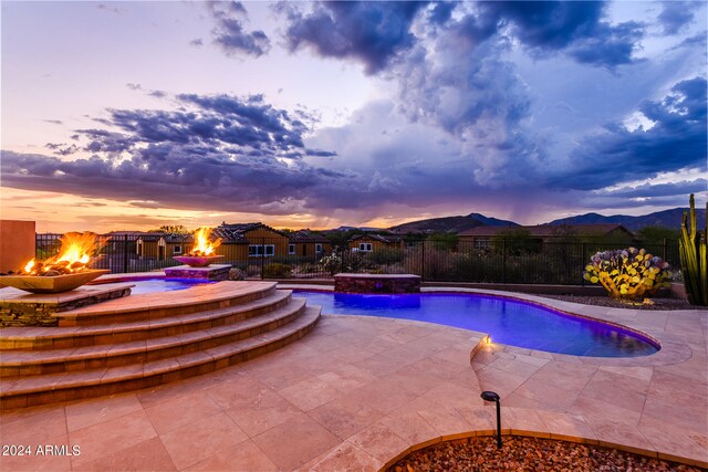 pool at dusk featuring a patio area and an outdoor fire pit