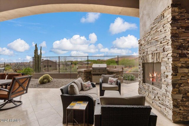 view of terrace with area for grilling, an outdoor living space with a fireplace, and exterior kitchen