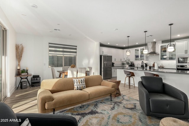 living room featuring sink and light hardwood / wood-style flooring