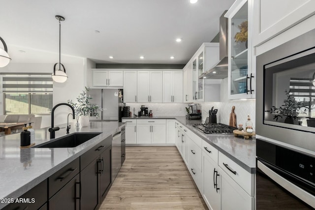 kitchen with appliances with stainless steel finishes, pendant lighting, white cabinetry, sink, and light stone countertops