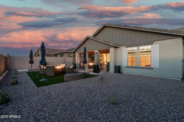 back house at dusk featuring a patio and an outdoor fire pit