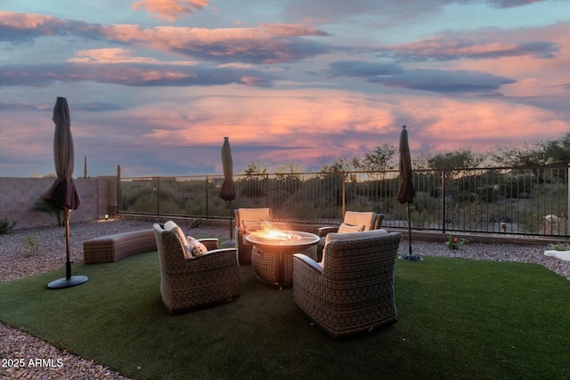 patio terrace at dusk featuring a yard and an outdoor fire pit