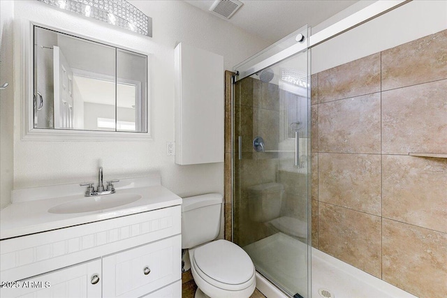 bathroom with a shower with shower door, toilet, and vanity