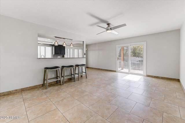 living room featuring ceiling fan, light tile patterned floors, and a textured ceiling