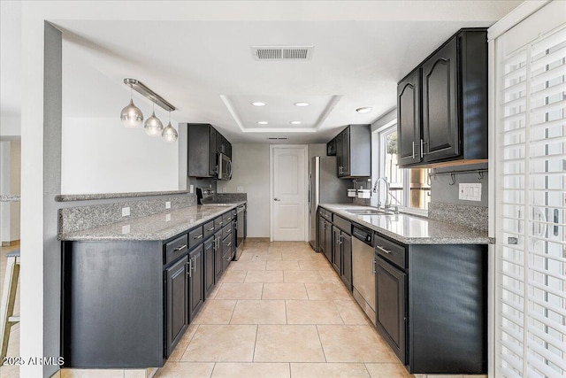 kitchen with appliances with stainless steel finishes, sink, a raised ceiling, light stone counters, and light tile patterned floors