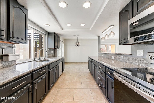 kitchen featuring decorative light fixtures, a raised ceiling, sink, appliances with stainless steel finishes, and light stone countertops