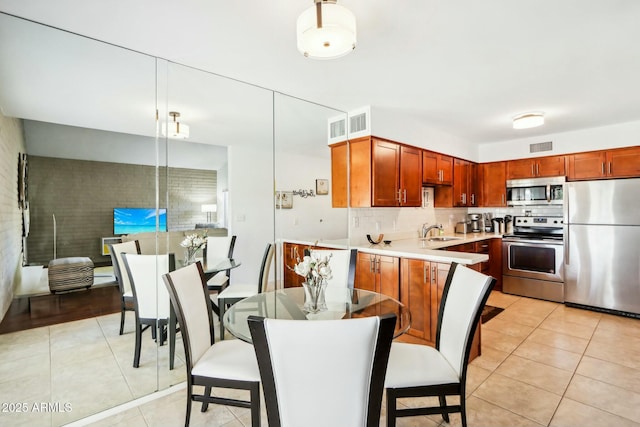 kitchen featuring appliances with stainless steel finishes, pendant lighting, sink, light tile patterned flooring, and tasteful backsplash