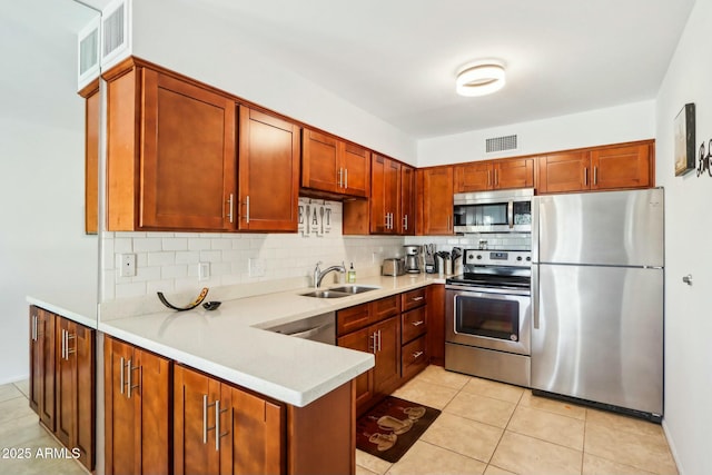 kitchen featuring sink, light tile patterned floors, kitchen peninsula, decorative backsplash, and appliances with stainless steel finishes