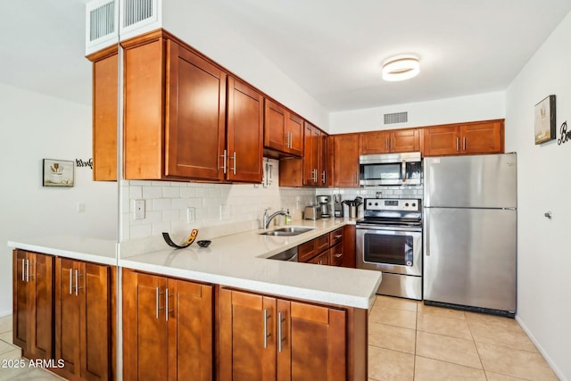 kitchen featuring appliances with stainless steel finishes, kitchen peninsula, light tile patterned floors, sink, and backsplash