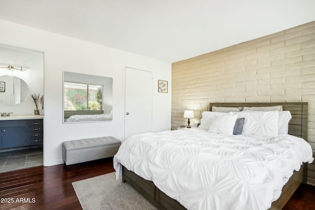 bedroom featuring sink, ensuite bathroom, and dark hardwood / wood-style flooring